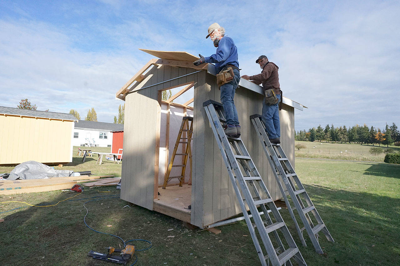 Larry Morrell, left, and Greg Kossow put a roof on an emergency shelter Thursday afternoon in Port Townsend. Along with Blue Heron Construction co-owner Randy Welle, the neighbors formed a volunteer group to build one shelter over several days as part of the Community Build Project, which aims to provide temporary-use shelters for the homeless during the coming winter months. (Nicholas Johnson/Peninsula Daily News)
