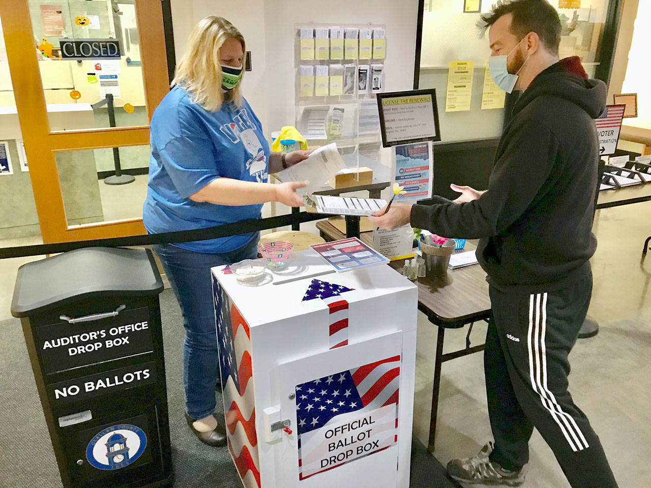 Angi Klahn, left, Clallam County Auditor’s Office accountant, helped process voter registration Friday, Oct. 30, 2020, for Seth Russell, formerly of Santa Cruz, Calif., who recently moved to Port Angeles with his partner and her brother. (Paul Gottlieb/Peninsula Daily News)