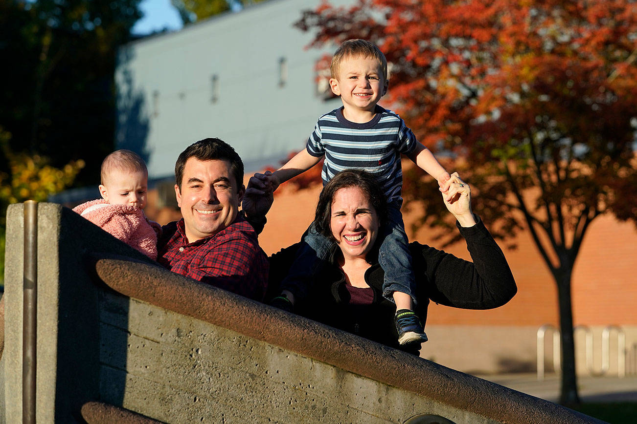 Parents Joelle and Ryan Wheatley pose with their children Anna, 9 months, and Jacob, 2, for a photo, Wednesday, Oct. 21, 2020, in Seattle. As with other families, they are dealing with stricter daycare rules on possible coronavirus symptoms that feel incompatible with the germy reality of modern childhood, where a toddler's sniffle or cough could bring 10 days of quarantine. (AP Photo/Elaine Thompson)