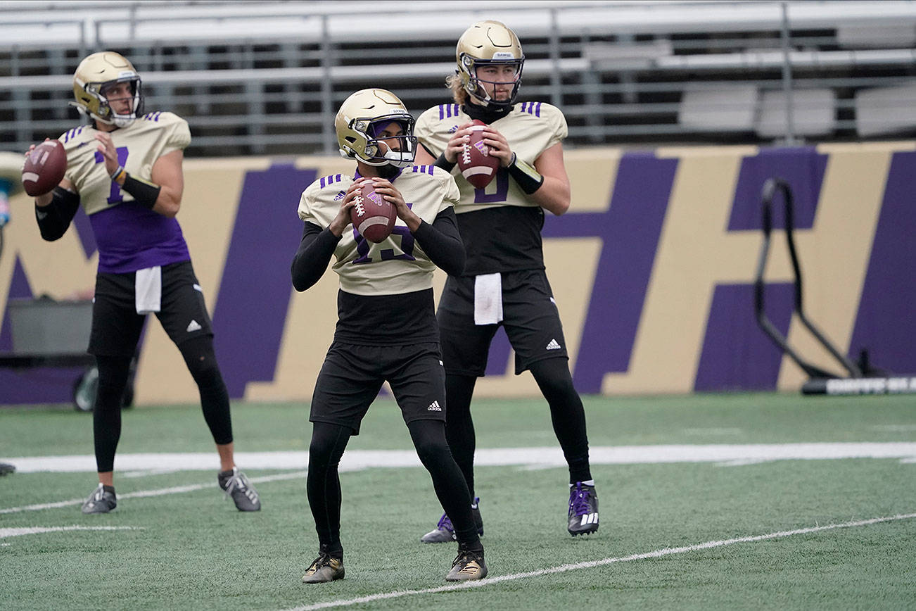 Washington quarterbacks Jaden Sheffey, center, Kevin Thomson, left, and Jacob Sirmon, right, pass in a group during NCAA college football practice, Friday, Oct. 16, 2020, in Seattle. (AP Photo/Ted S. Warren)