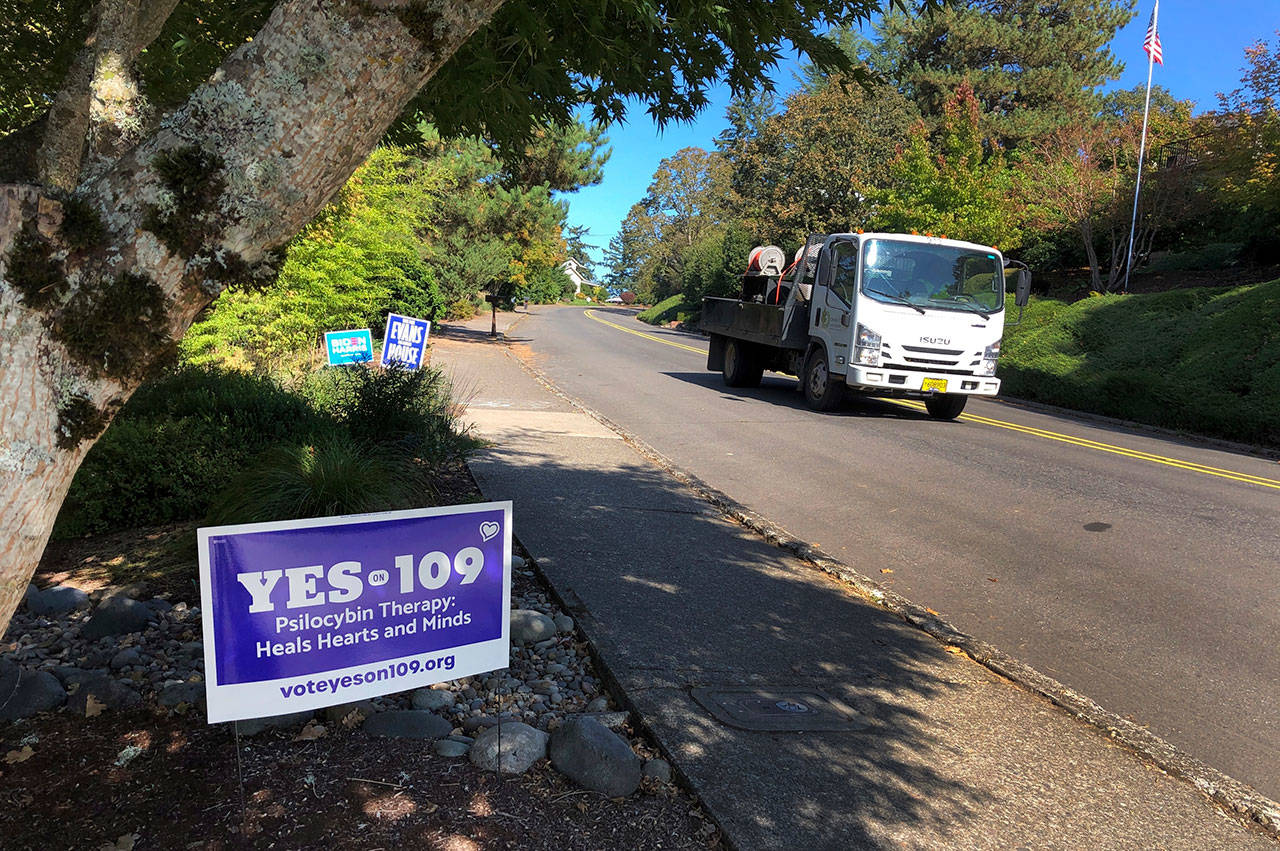 A truck drives past a sign supporting a ballot measure that would legalize controlled, therapeutic use of psilocybin mushrooms Friday, Oct. 9, 2020 in Salem, Ore. War veterans with PTSD, terminally ill patients and others suffering from anxiety are backing the ballot measure. (Andrew Selsky/Associated Press)