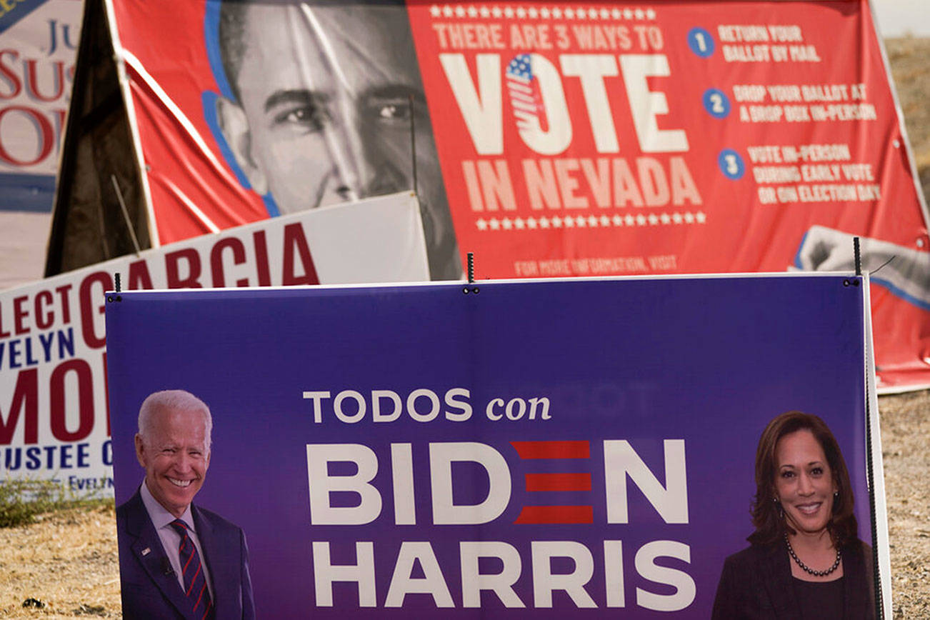 A campaign sign supporting Democratic presidential candidate former Vice President Joe Biden and running mate Kamala Harris stands in front of a vote sign showing former President Barack Obama near the Clark County Election Department in North Las Vegas, Nev., Friday, Nov. 6, 2020. (AP Photo/Jae C. Hong)
