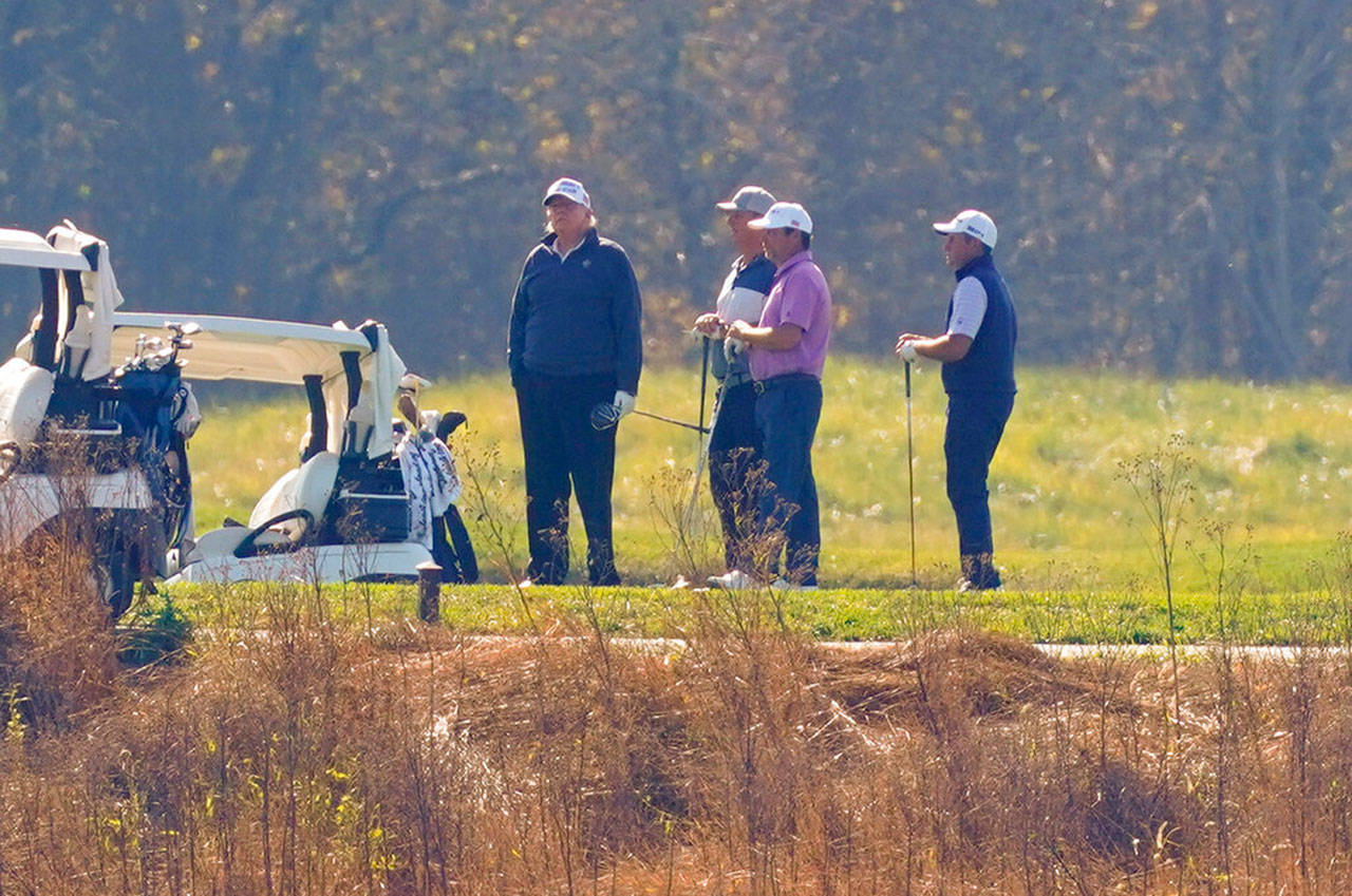 President Donald Trump, center standing, participates in a round of golf at the Trump National Golf Course on Saturday, Nov. 7, 2020, in Sterling, Va. (Patrick Semansky/Associated Press)