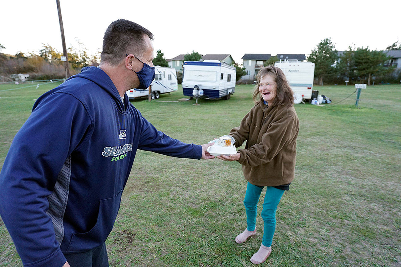 Chef Troy Murrell with Bayside Housing and Services, left, hands a hot meal to Janna Hall on Sunday at the Jefferson County Fairgrounds campground in Port Townsend. Hall, who has bipolar disorder, said she has been homeless in Port Townsend for eight years and currently lives in a tent at the fairgrounds. Nicholas Johnson/Peninsula Daily News
