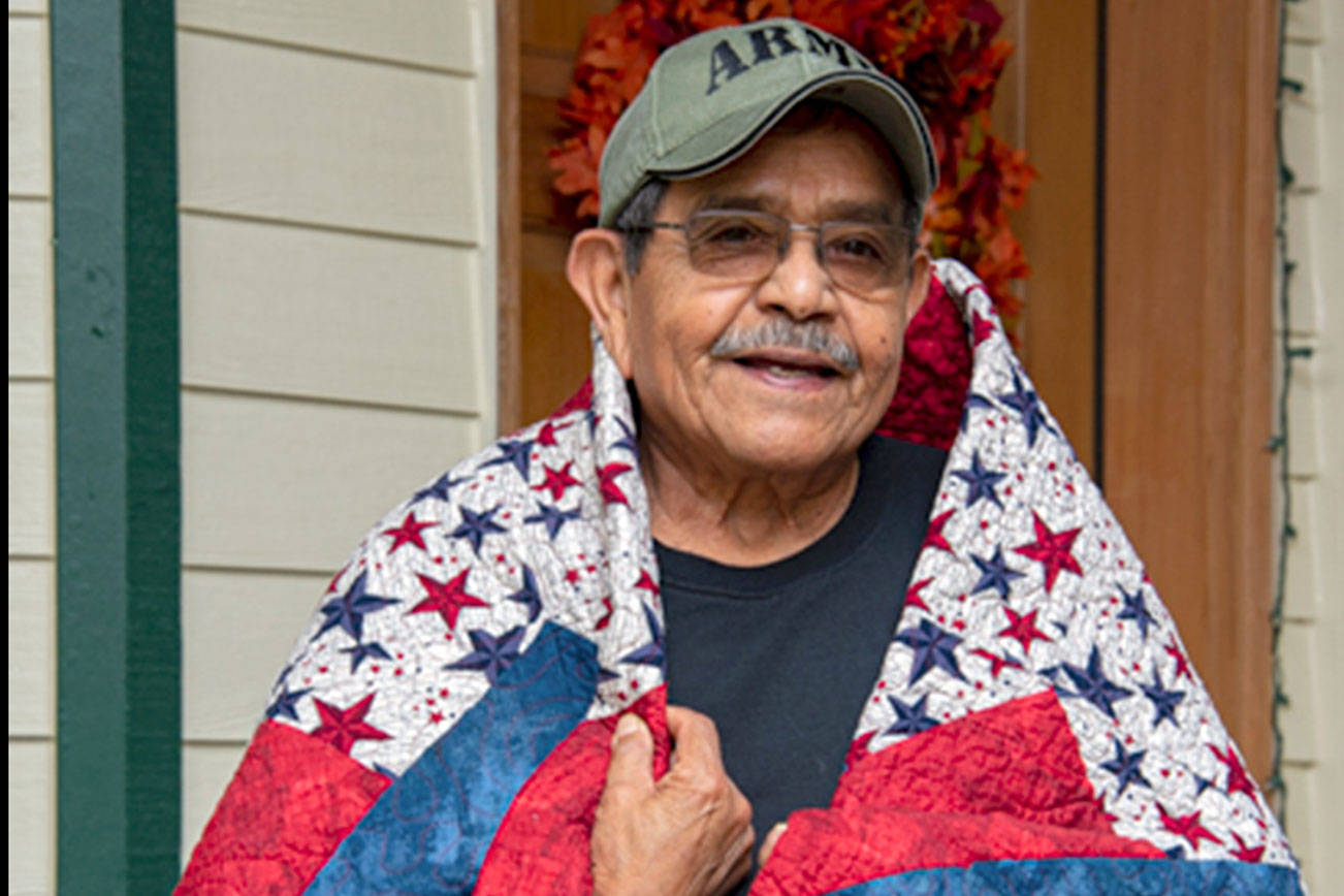 Daniel J. Merino, U.S. Army veteran, is wrapped in the quilt that was recently made for and presented to him by the North Olympic Peninsula Quilts of Valor group. (Photo courtesy of Christopher Bates Photography)