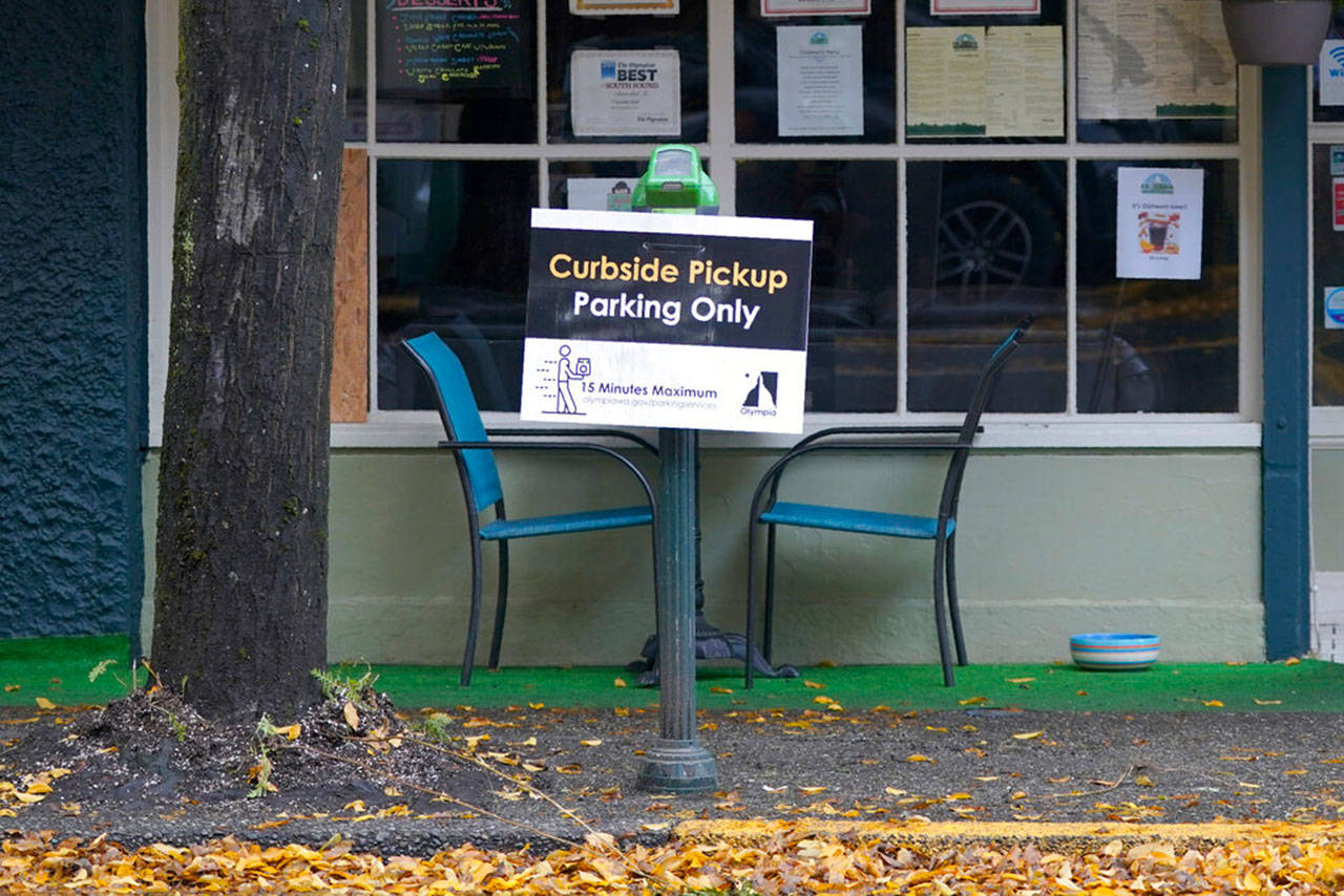 A sign for curbside pickup is shown outside the Cascadia Grill, Sunday, Nov. 15, 2020, in downtown Olympia, Wash. Washington Gov. Jay Inslee announced Sunday that beginning Wednesday, Nov. 18, 2020, indoor dining will not be allowed and that restaurants and bars will be limited to to-go service and outdoor dining with tables seating no more than five people. Restrictions and limitations were also announced for gyms, grocery stores, and other businesses as the state continues to combat a rising number of coronavirus cases. (Ted S. Warren/Associated Press)