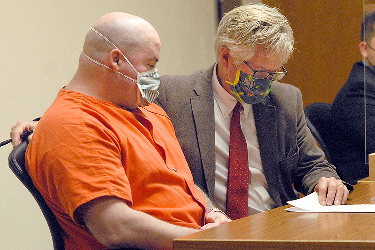 Ryan Warren Ward, left, looks over court papers with attorney Lane Wolfley during Ward's sentencing for three counts of aggravated first-degree murder and multiple counts of theft and firearms violations on Thursday in Clallam County Superior Court in Port Angeles. (Keith Thorpe/Peninsula Daily News)