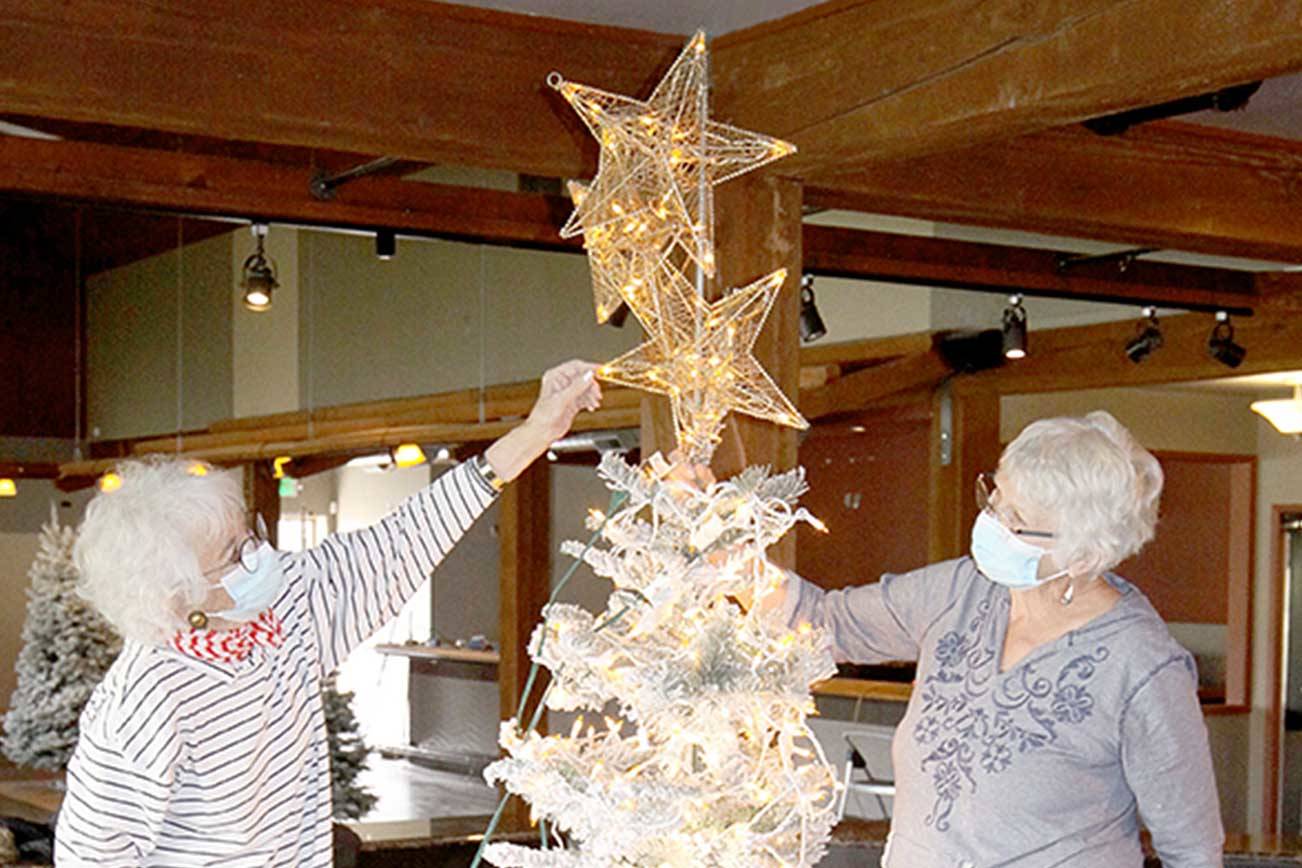 Betsy Schultz, left, and Sue Chance work on their tree Saturday morning inside Edna’s Place. Their tree, based on the Captain Joseph House Foundation, is called “Starway to Living." Today is the last day for trees to be decorated. (Dave Logan/For Peninsula Daily News)