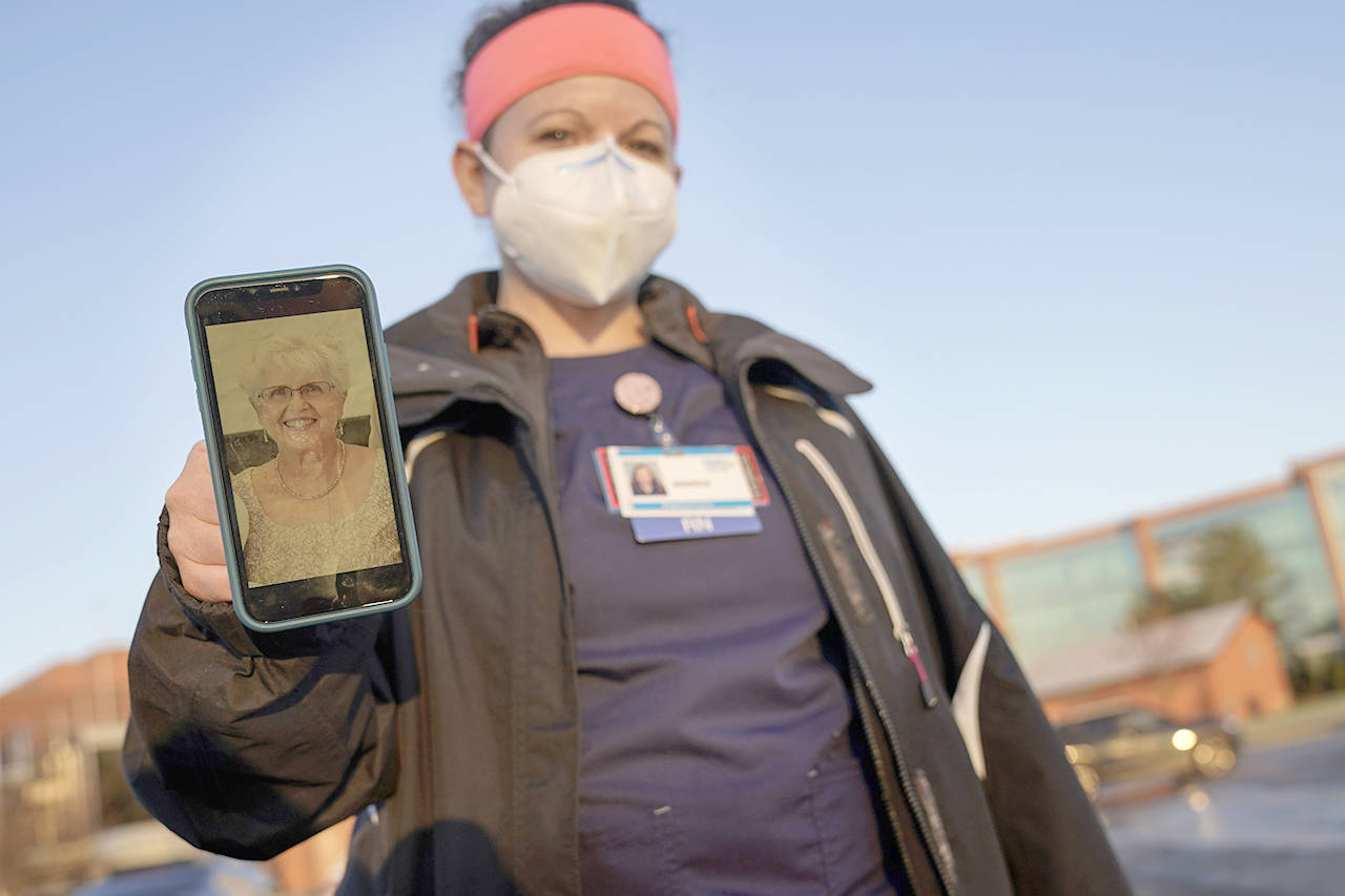 Nurse Jessica Franz, shows a photo of her mother-in-law, Elaine Franz, outside Olathe Medical Center after working the graveyard shift Thursday in Olathe, Kan. Elaine Franz died Nov. 10, one day before her 78th birthday, after contracting COVID-19. (Charlie Riedel/The Associated Press)