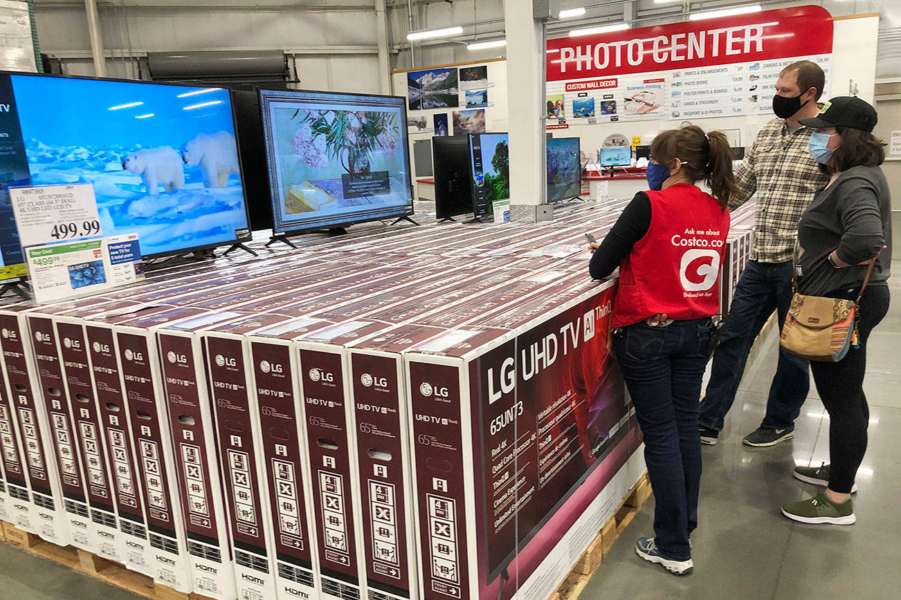 A sales associate helps customers as they consider the purchase of a big-screen television at a Costco warehouse on Wednesday, Nov. 18, 2020, in Sheridan, Colo.  U.S. consumer confidence fell to a reading of 96.1 in November as rising coronavirus cases pushed Americans’ confidence down to the lowest level since August. The Conference Board said the November reading represented a drop from a revised 101.4 in October.  (AP Photo/David Zalubowski)