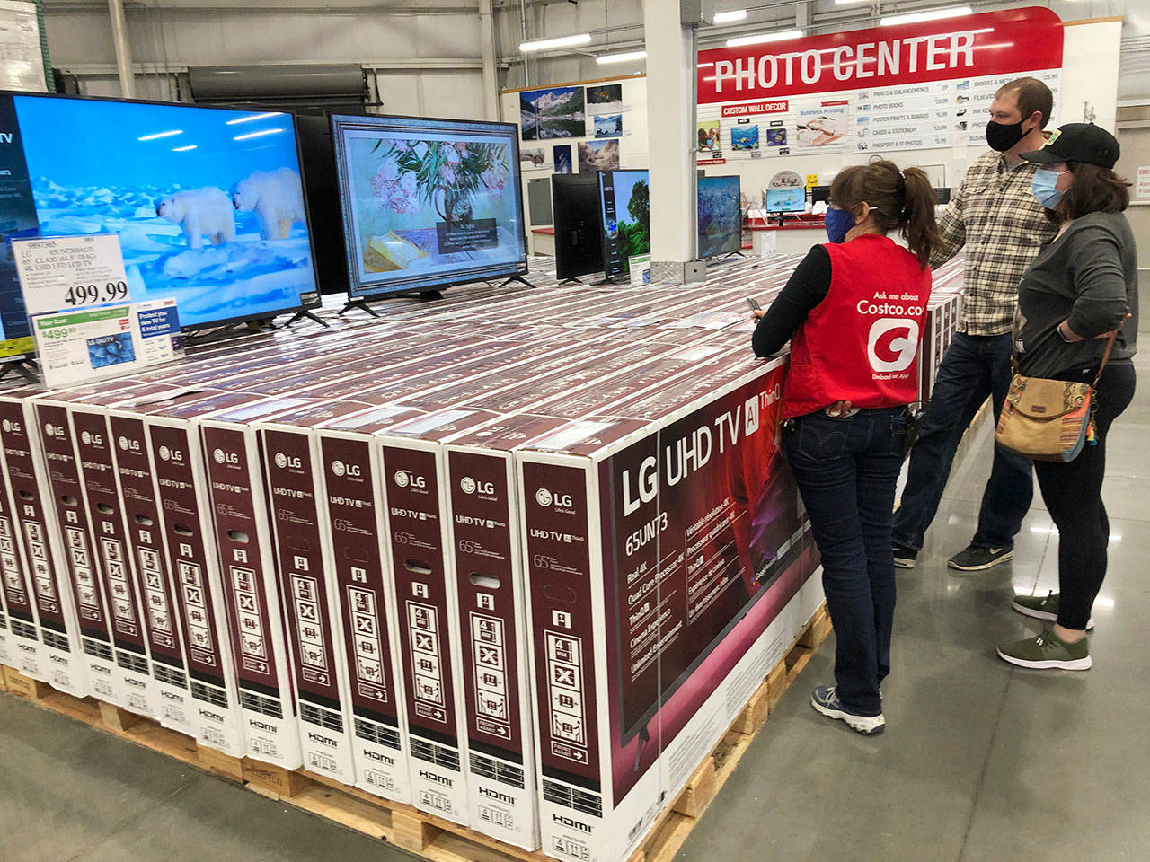 A sales associate helps customers as they consider the purchase of a big-screen television at a Costco warehouse Wednesday, Nov. 18, 2020, in Sheridan, Colo. U.S. consumer confidence fell to a reading of 96.1 in November as rising coronavirus cases pushed Americans’ confidence down to the lowest level since August. The Conference Board said the November reading represented a drop from a revised 101.4 in October. (David Zalubowski/The Associated Press)