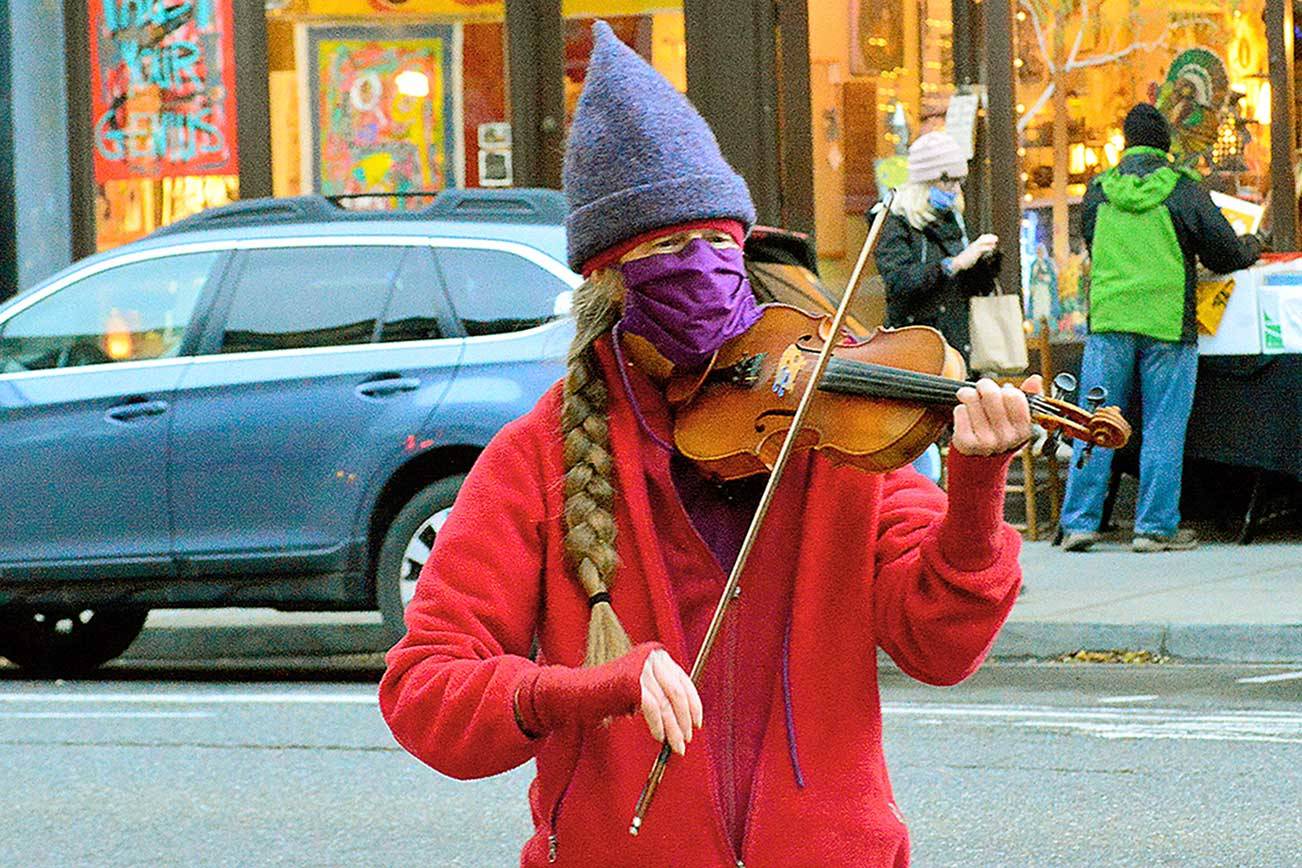 As holiday shopping ramps up in downtown Port Townsend, Kim Thomson offers a solo violin performance at Water and Taylor streets. A maker of hats and music, Thomson opened her violin case to accept tips for the Jefferson County Food Bank. (Diane Urbani de la Paz/Peninsula Daily News)