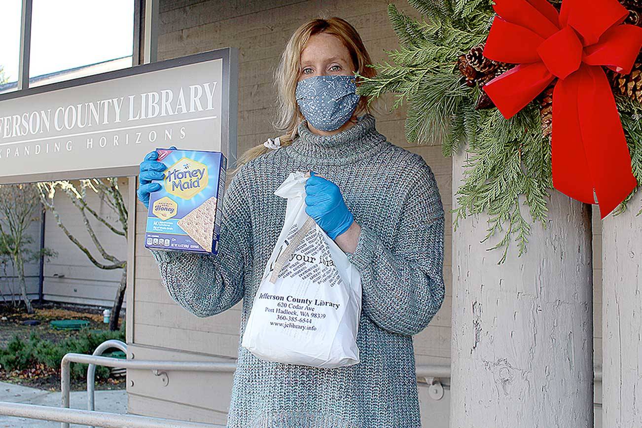 Quintana Kelley, library assistant at the Jefferson County Library, holds the gingerbread house-making kit that the library is passing out for its annual edible house-building competition. Registration to pick up the free kits closes Saturday, and photos of the finished houses are due by Dec. 13. (Zach Jablonski/Peninsula Daily News)