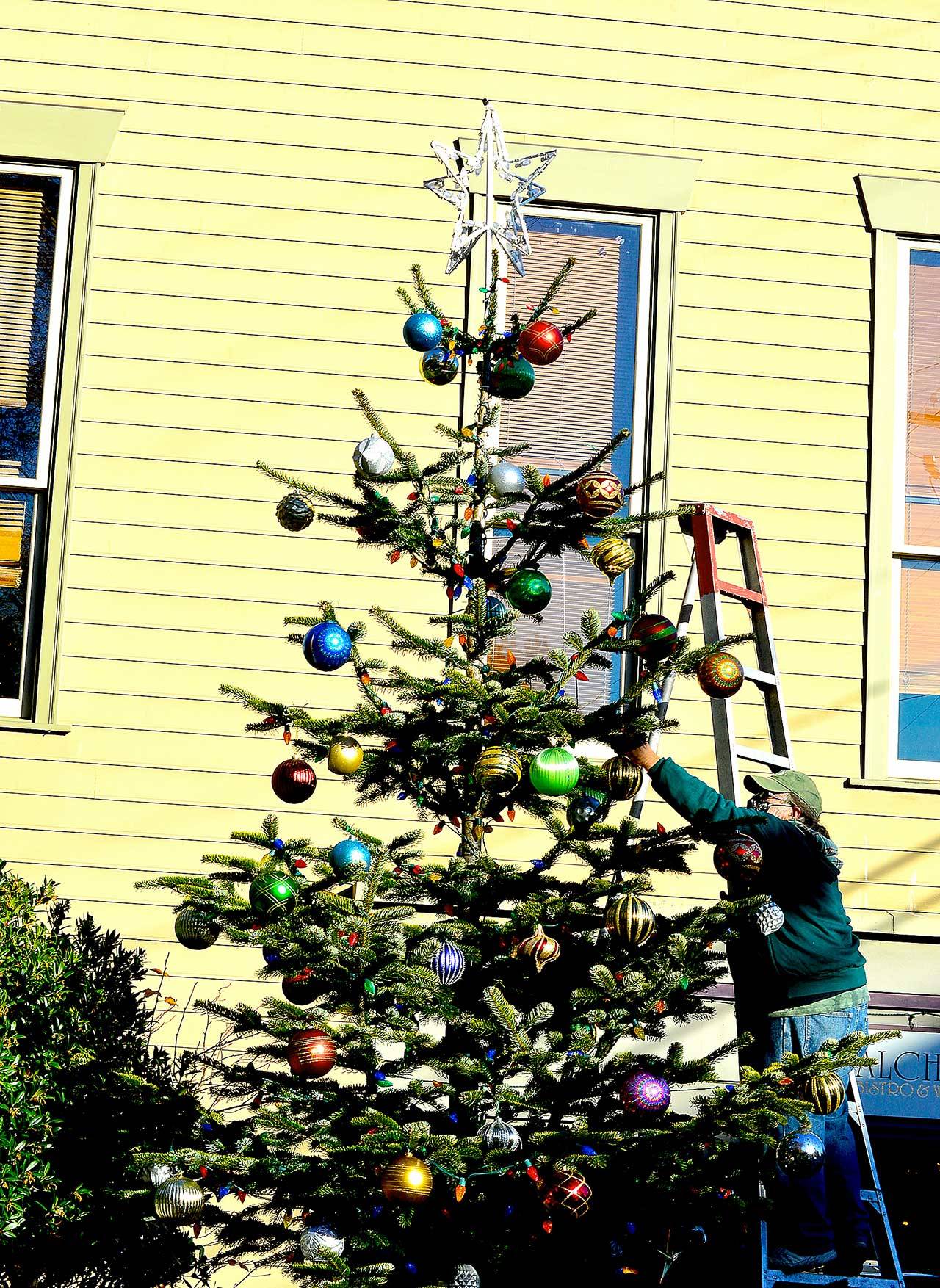 Downtown Port Townsend’s 16-foot Nordman fir got its ornaments, courtesy of longtime Main Street decorator Michael Rosser, in anticipation of the virtual tree lighting around dusk Saturday. The lighting will be shared on the Port Townsend Main Street Program Facebook page. (Diane Urbani de la Paz/Peninsula Daily News)