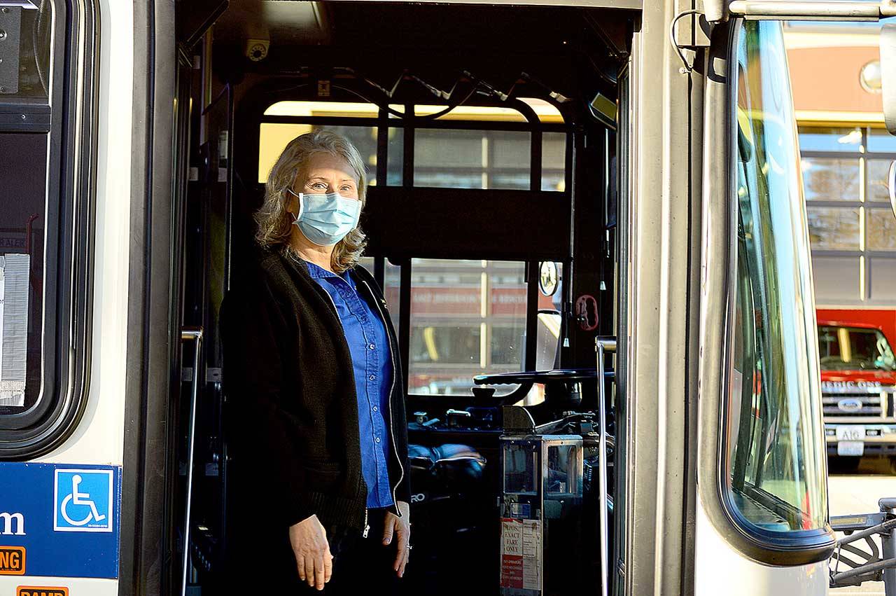 Jefferson Transit operator Linda Baumgaertner steps out from behind the barrier around her driver’s seat. (Diane Urbani de la Paz/Peninsula Daily News)