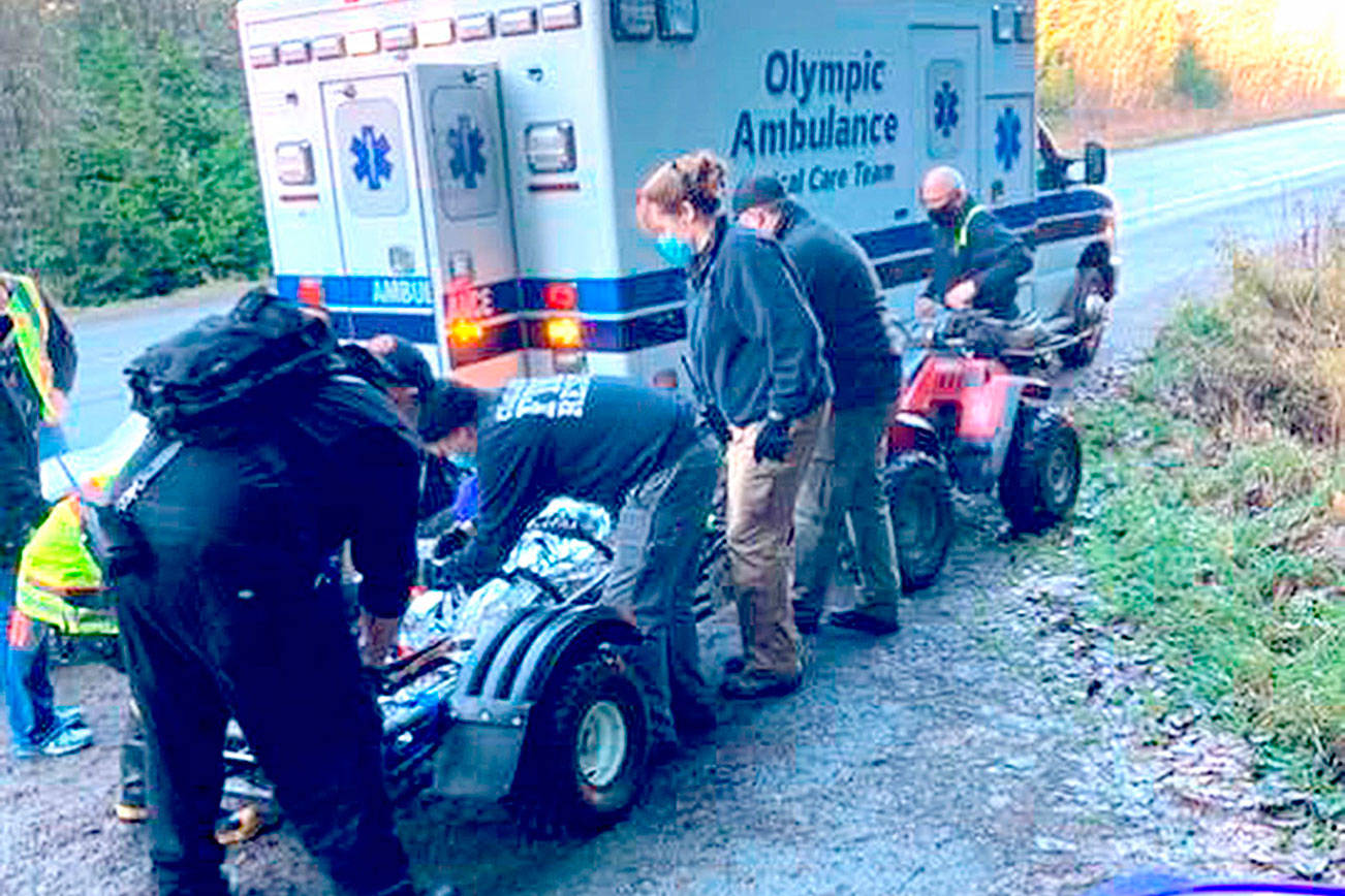 An injured biker is treated Saturday by Clallam Fire District No. 2 personnel after being brought down from the backcountry after a wreck. (Photo courtesy of Mike McVaugh)