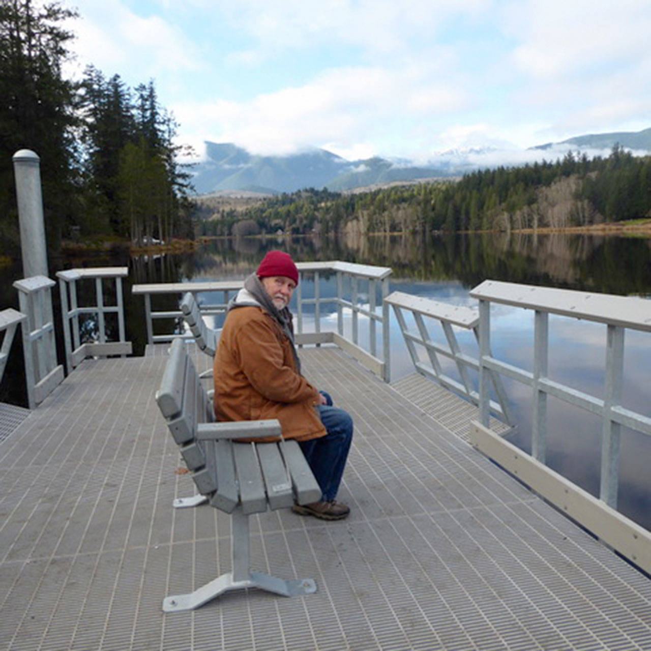 Quilcene’s Ward Norden sits on a bench at the recently constructed fishing pier at Lake Leland County Park. The Lake Leland day use park, boat ramp, fishing dock and waterfront area are open after a construction project by the state Department of Fish and Wildlife. (Photo courtesy of Holly Bauman)