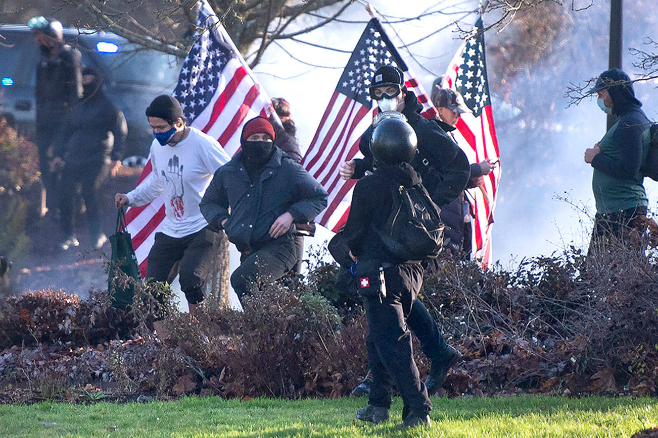 Supporters of President Donald Trump and antifa supporters clashed with Washington state police on the state Capitol Campus in Olympia, Wash., Saturday, Dec. 12, 2020. Police in Olympia declared a riot early Saturday afternoon and arrested at least one person as groups with different points of view held simultaneous protests. (The Olympian via AP)