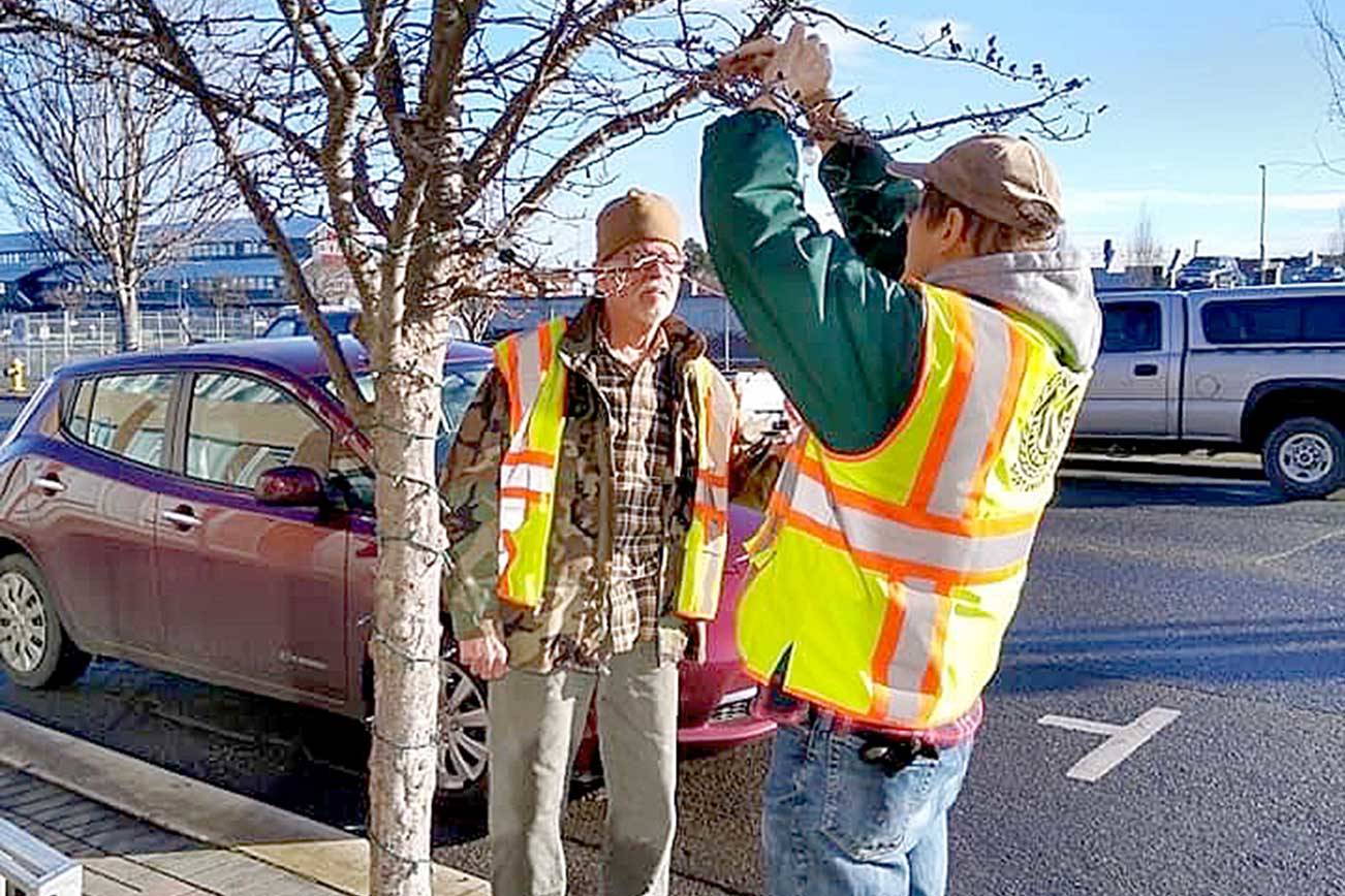 Olympic Kiwanis members Frank Bruni and Tim Crowley work to fix holiday lights in downtown Port Angeles. (Olympic Kiwanis Club)