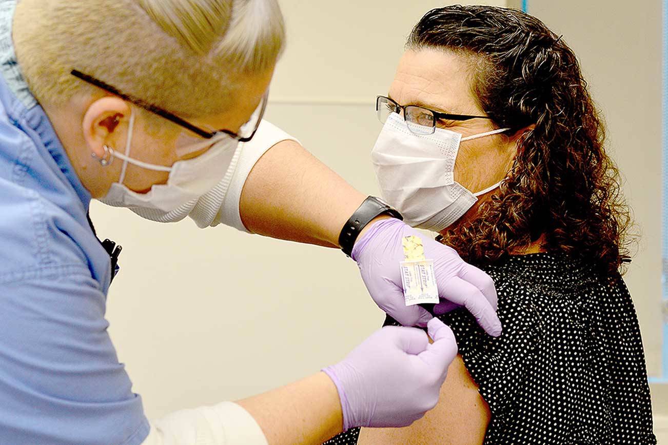 Nurse Jess Cigalotti administers the North Olympic Peninsula's first COVID-19 vaccine Wednesday to Dr. Tracie Harris, an internist and hospitalist who cares for COVID patients at Jefferson Healthcare hospital. (Diane Urbani de la Paz/Peninsula Daily News)