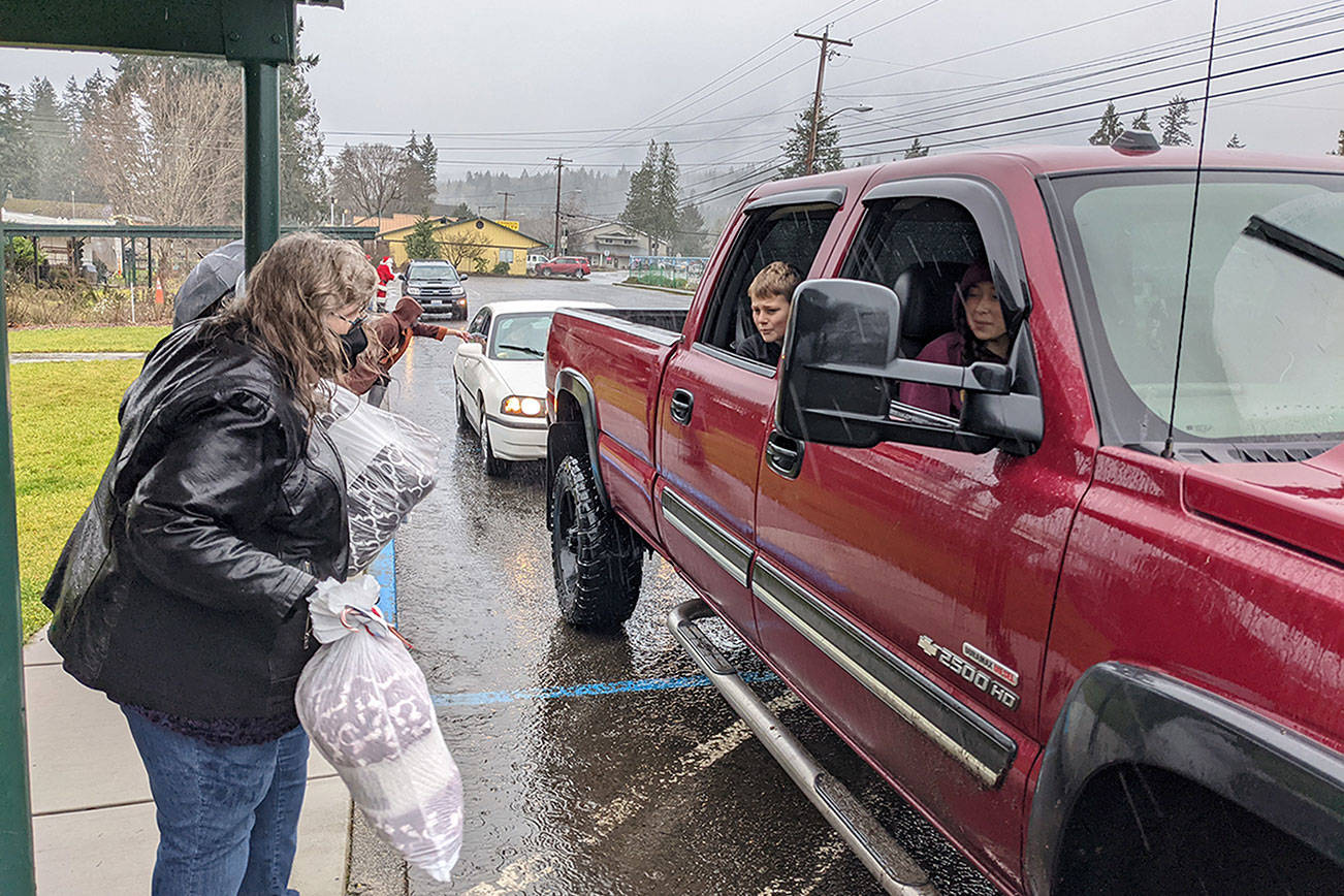 Quilcene School District administrative assistant Carrie Thompson tosses a blanket to  a student sitting in a truck with her family, during the district's "Winter Warm-up" event on Wednesday. (Zach Jablonski/Peninsula Daily News)