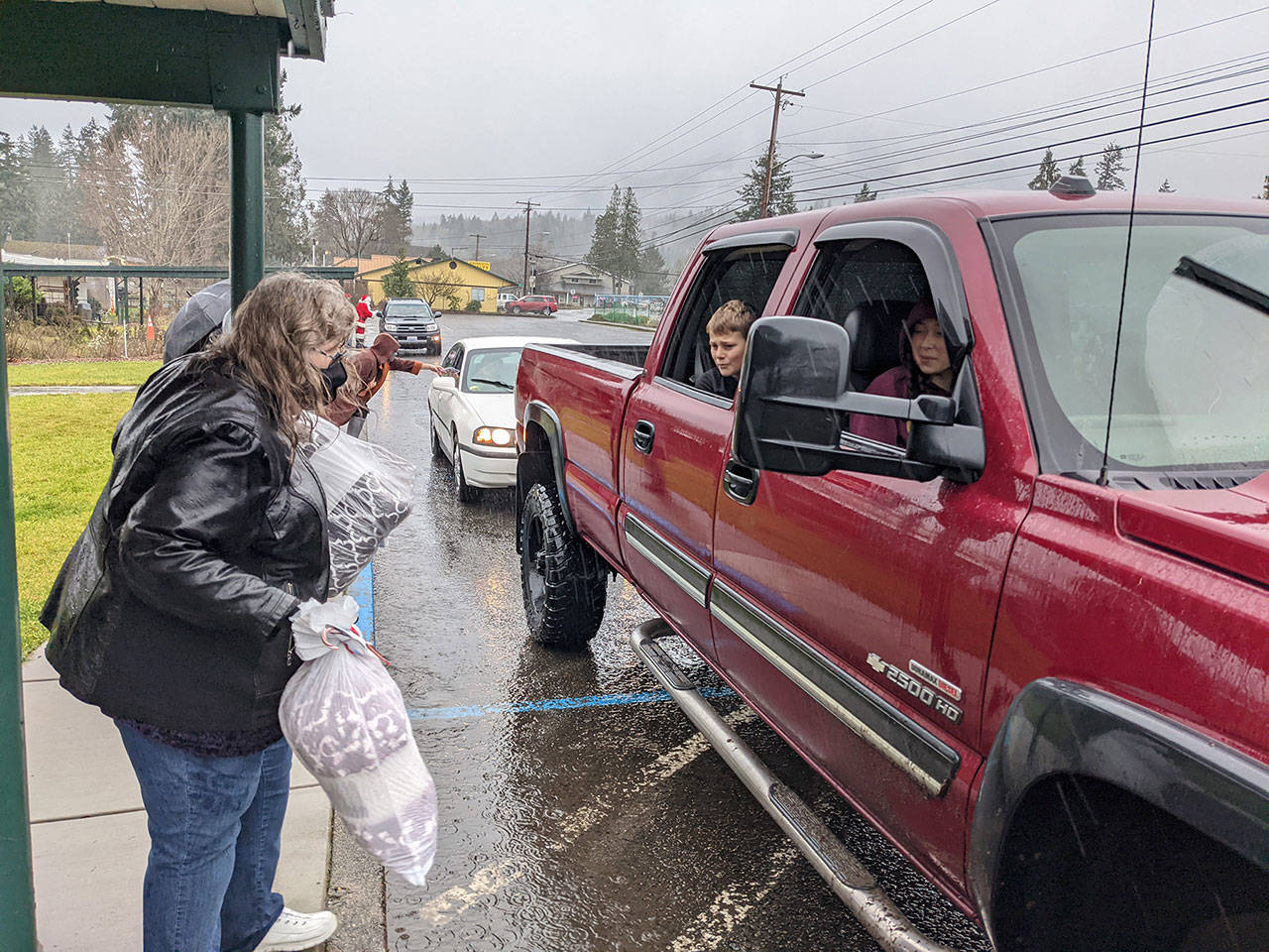 Quilcene School District administrative assistant Carrie Thompson tosses a blanket to a student sitting in a truck with her family during the district’s “Winter Warm-up” event Wednesday, Dec. 16, 2020. (Zach Jablonski/Peninsula Daily News)