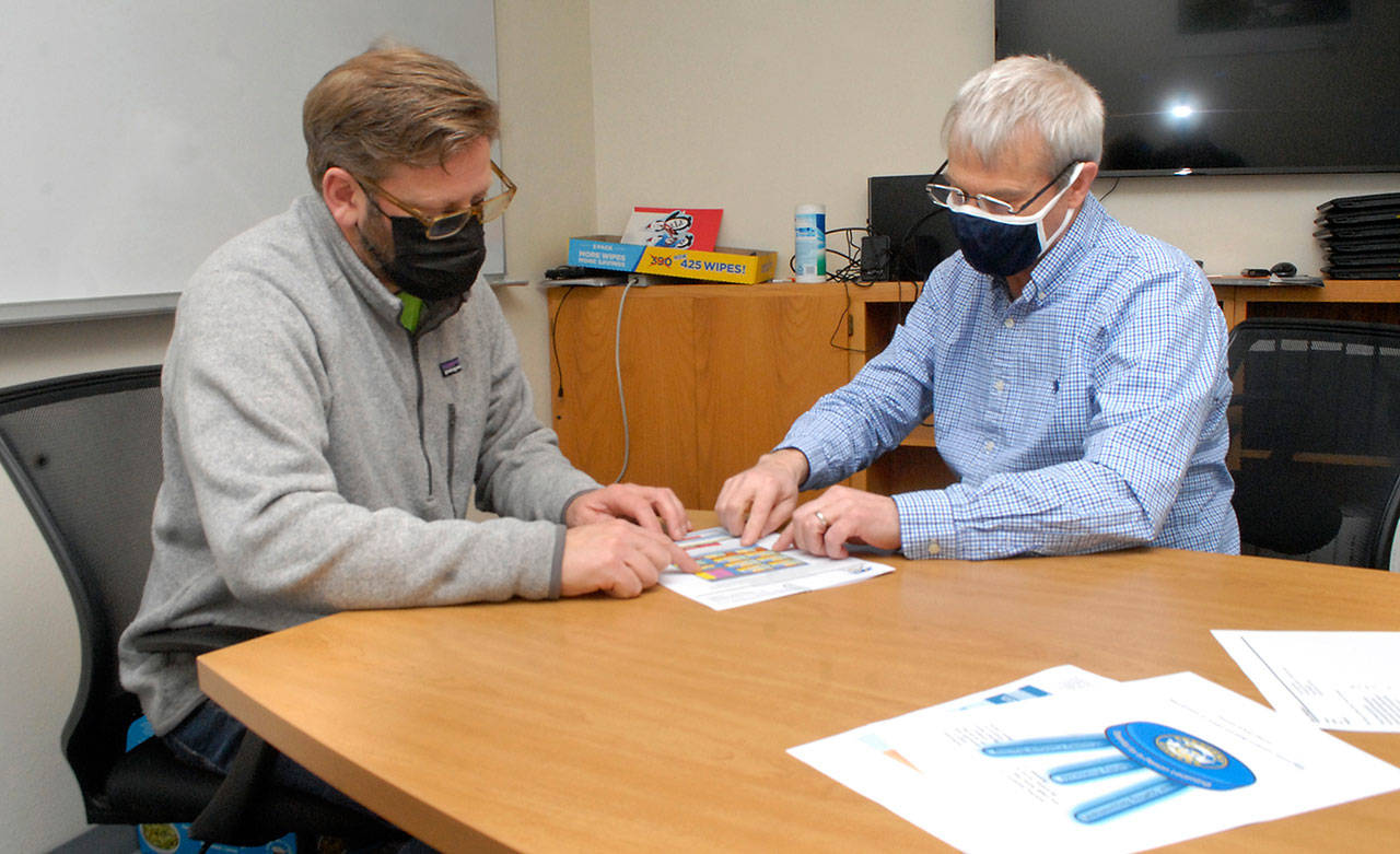 State Rep. Mike Chapman, left, and Crescent School Superintendent Dave Bingham examine enrollment statistics for the school district on Thursday in Joyce. (Keith Thorpe/Peninsula Daily News)