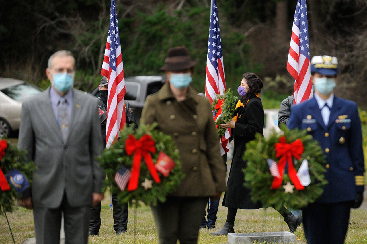 Staff Sgt. Jessica Elizalde-Broders, a U.S. Army veteran, looks to lay a ceremonial wreath at Sequim View Cemetery Saturday. In the foreground are, from left, Cmdr. Bill Benedict (U.S. Navy, ret.), Lance Cpl. Holly Rowan (U.S. Marine Corps veteran) and Cmdr. Joan Snaith (U.S. Coast Guard, Air Station Port Angeles). (Michael Dashiell/Olympic Peninsula News Group)