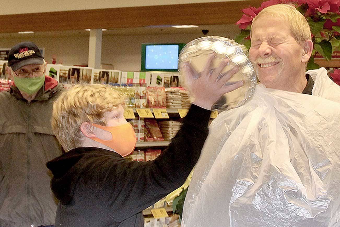 Sequim Mayor William Armacost takes a whipped cream pie in the face from Ben Clemens, 10, the son of Port Angeles Mayor Kate Dexter, at the Port Angeles Safeway store on Lincoln Street, the culmination of a challenge between Safeway stores in the two towns to see which could raise more donations for local food banks. (Dave Logan/For Peninsula Daily News)