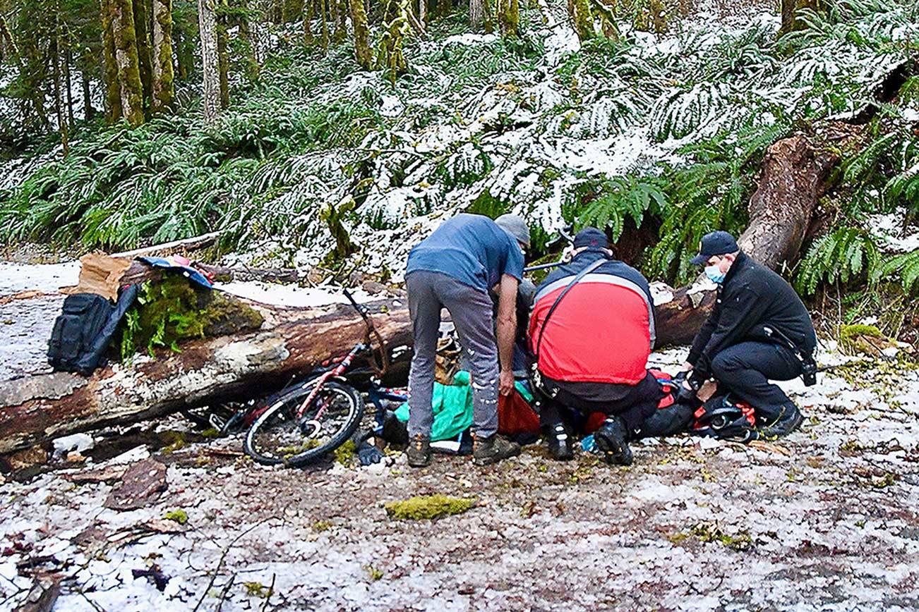 Rescue workers attend to a man who was injured after he was struck by a falling tree while he was riding his bicycle in the Elwha Valley. (Clallam County Fire District 2)