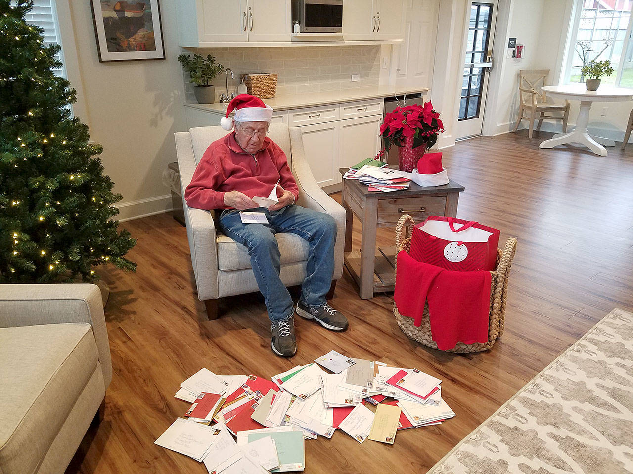 Rodney Hofman opens one of hundreds of Christmas cards sent to him and fellow Dungeness Courte Memory Care residents following a request from Hofman’s family members on social media. (Photo courtesy of Dungeness Courte Memory Care)