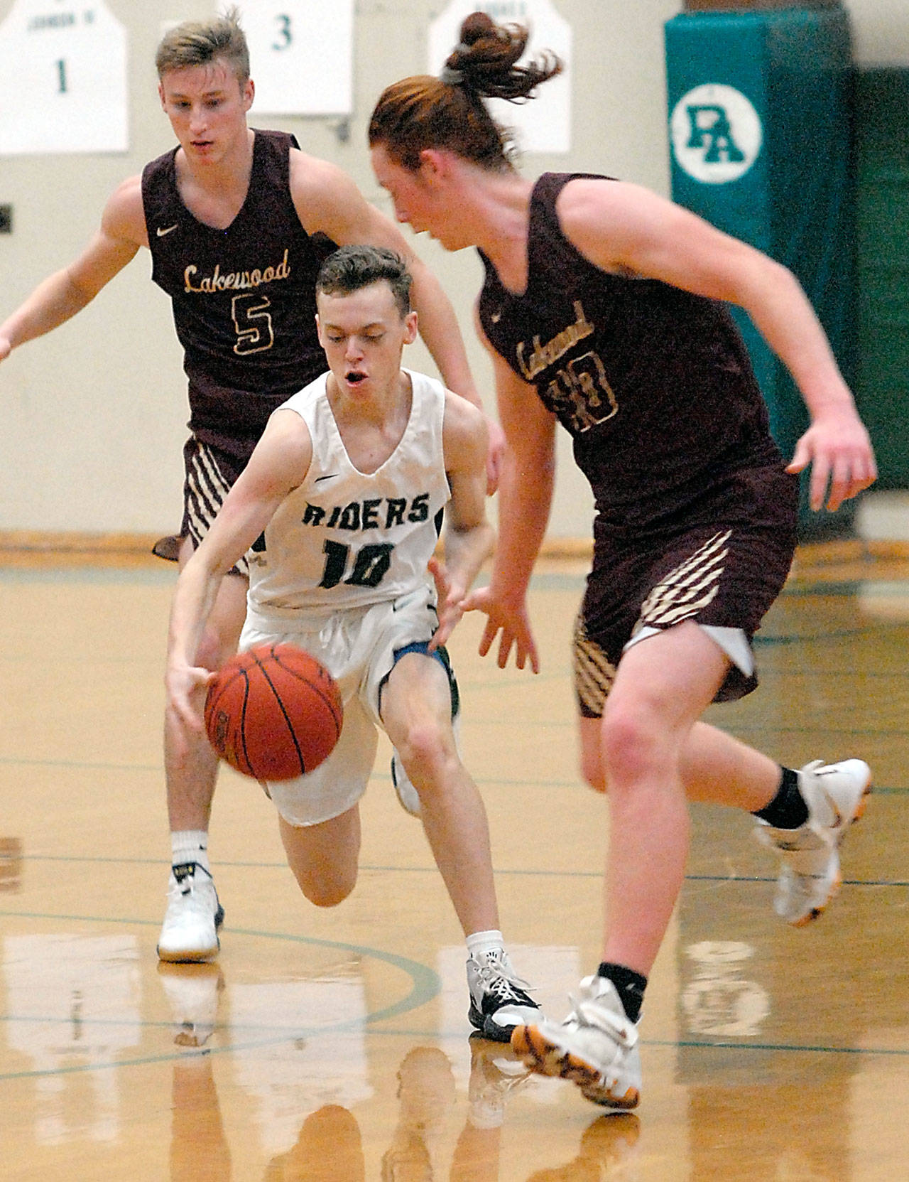 Port Angeles’ Dru Clark, center, drives down the court surrounded by Lakewood’s Shae Dixon, left, and Andrew Molloy during a 2019 game in Port Angeles. (Keith Thorpe/Peninsula Daily News file)