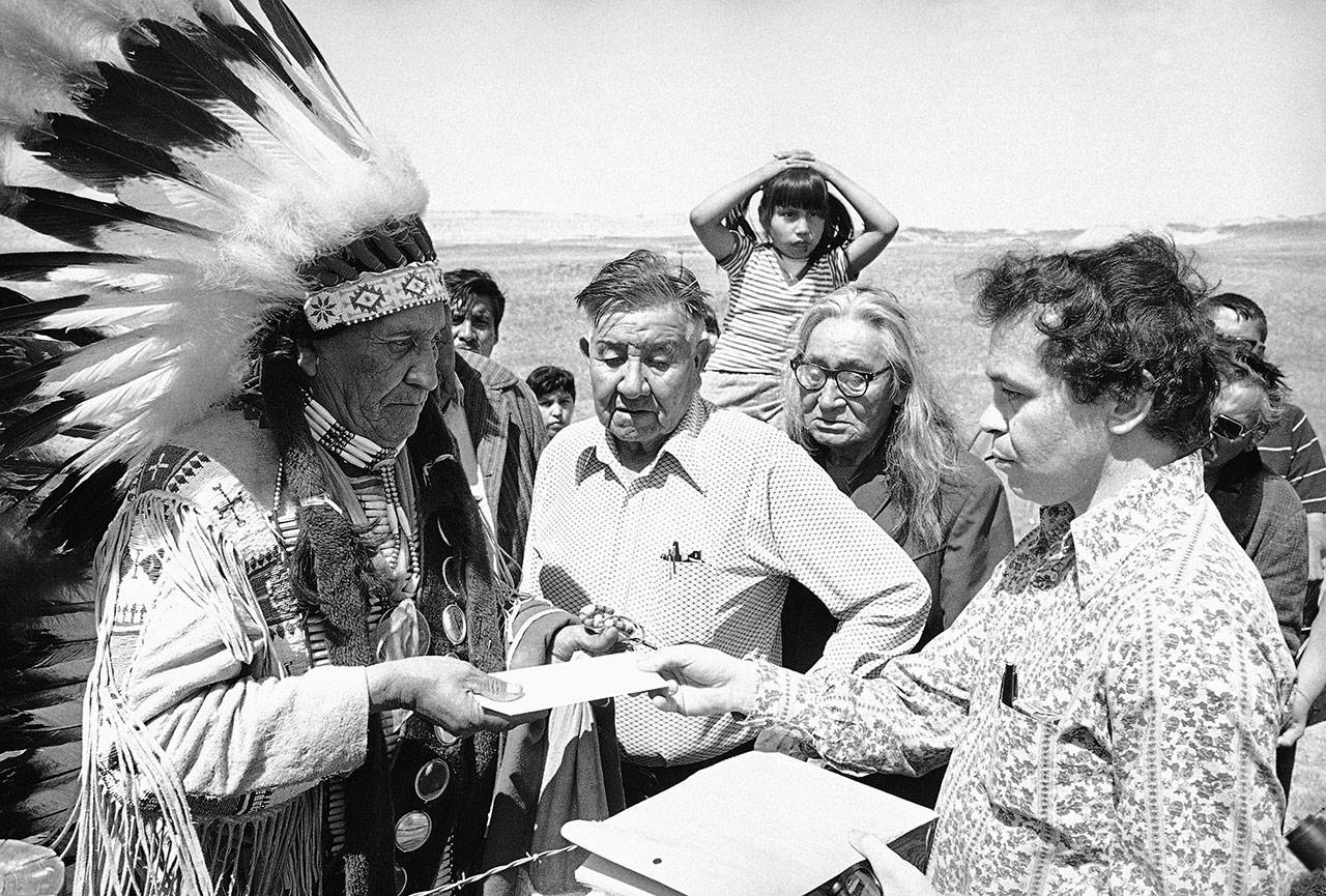In this May 5, 1973 file photo Hank Adams, right, permanent representative of the Indians Trial of Broken Treaties presents letter from the White House to traditional Sioux Chief Frank Fools Crow, left, at border of Pine Ridge Reservation in Scenic,. S.D. (AP Photo)