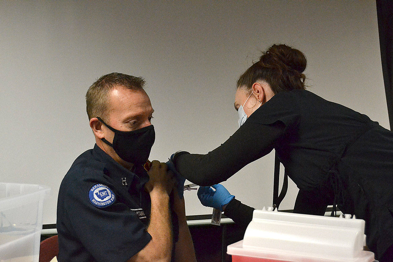 Nurse Kelly Bower with the Jamestown Family Health Clinic gives a Moderna COVID-19 vaccine to Capt. Derrell Sharp with Clallam County Fire District 3 on Tuesday at the fire stations headquarters. (Matthew Nash/Olympic Peninsula News Group)