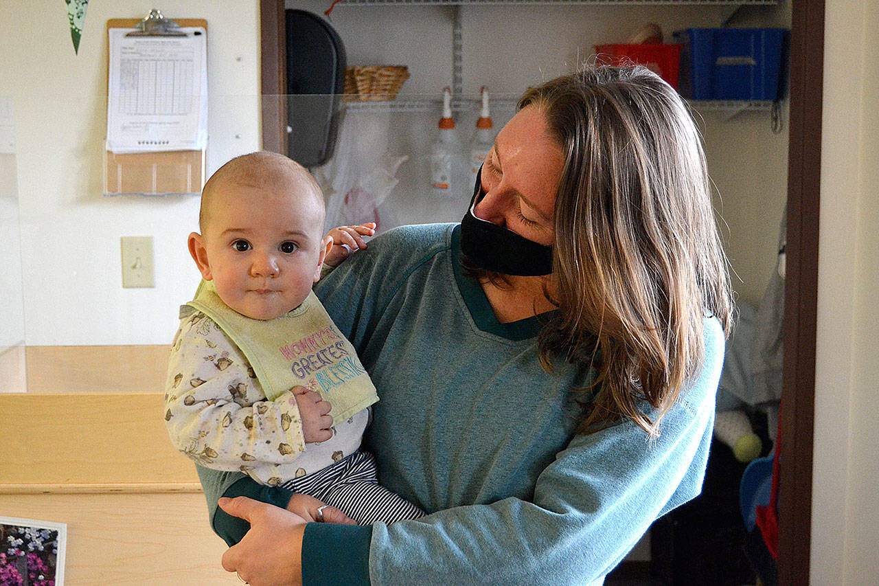Bethany McKim, infant room teacher at Sequim’s Little Explorers Early Learning Center, cares for 7-month-old Oisin last month. Owners of the center said they’ve had difficulty hiring during the pandemic, and that has led to limited hours. (Matthew Nash/Olympic Peninsula News Group)