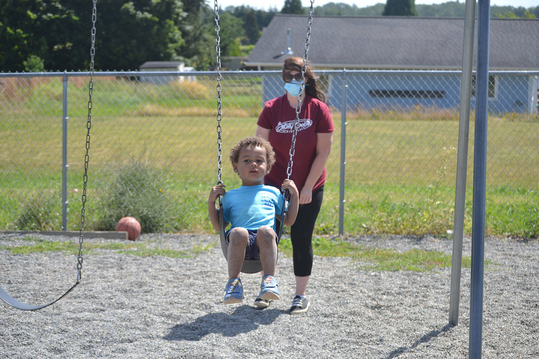 Sarah Schmedding plays with Harry Piper on the swings at Bibity Bobity last June. Space for child care has stayed mostly the same at Bibity Bobity in Carlsborg with school-aged children being the biggest shift, owner-director Nicole Goettling said. They used to come after school but now stay all day due to distance learning in-place during the pandemic. (Matthew Nash/Olympic Peninsula News Group file)