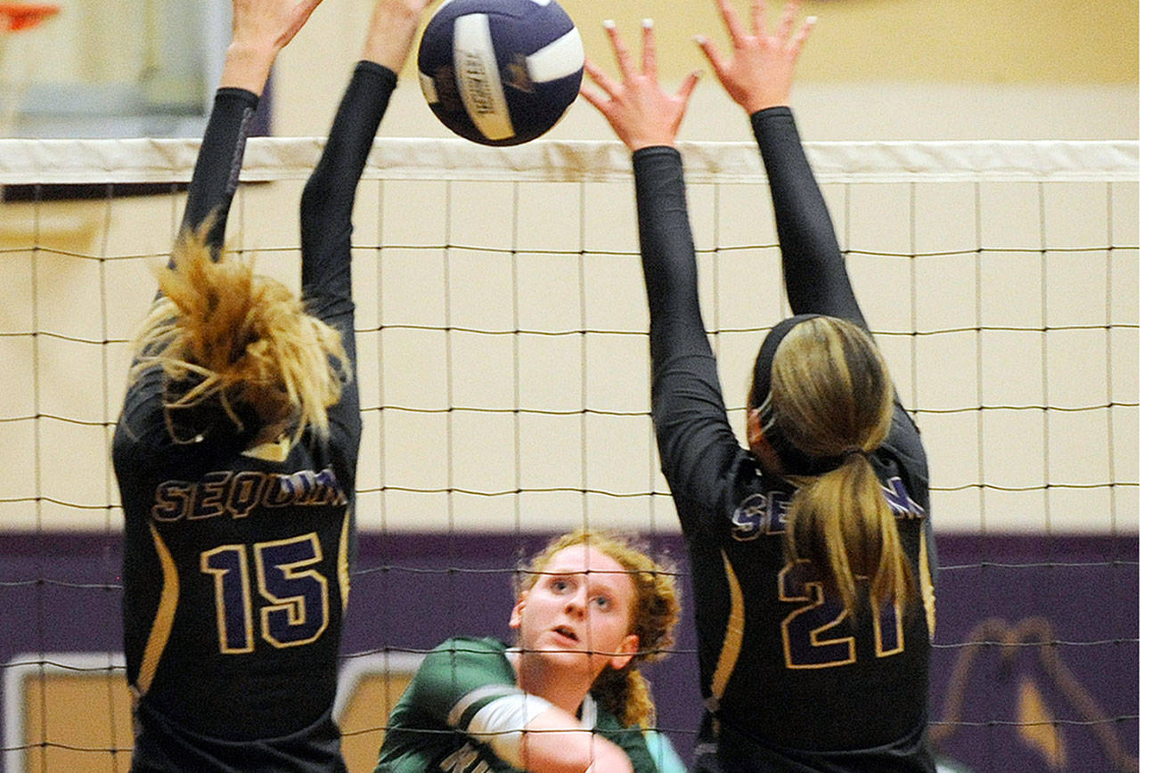 Port Angeles' Kennedy Bruch, center, returns the volleyball between the hands of Sequim's Kendall Hastings, left, and Kali Wiker during an October 2019 match in Sequim. (Michael Dashiell/Olympic Peninsula News Group)