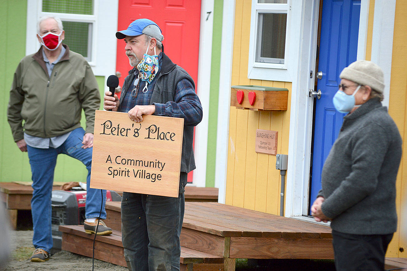 Builder Randy Welle holds up the new sign for the village of individual shelters near the Community United Methodist Church in Port Hadlock. Pastor Scott Rosekrans, left, and original project manager Peter Bonyun joined him in Thursday's blessing ceremony. Diane Urbani de la Paz/Peninsula Daily News