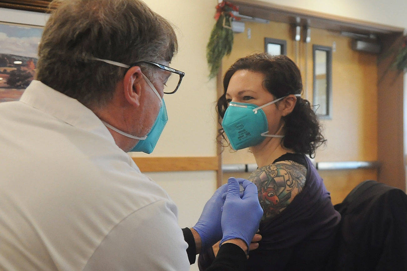 Robin Worth-McIntyre, a nurse technician at Avamere Olympic Rehabilitation of Sequim, gets a Pfizer vaccine shot from Walgreens pharmacist Steve Sommers.  (Michael Dashiell/Olympic Peninsula News Group)