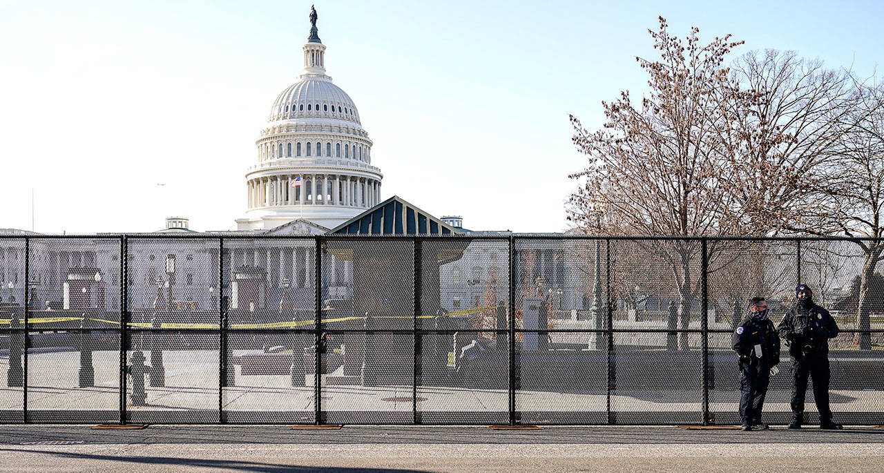 Capitol police officers stand outside of fencing that was installed around the exterior of the Capitol grounds Thursday in Washington. The House and Senate certified the Democrat’s electoral college win early Thursday after a violent throng of pro-Trump rioters spent hours Wednesday running rampant through the Capitol. A woman was fatally shot, windows were bashed and the mob forced shaken lawmakers and aides to flee the building, shielded by Capitol Police. (AP Photo/John Minchillo)