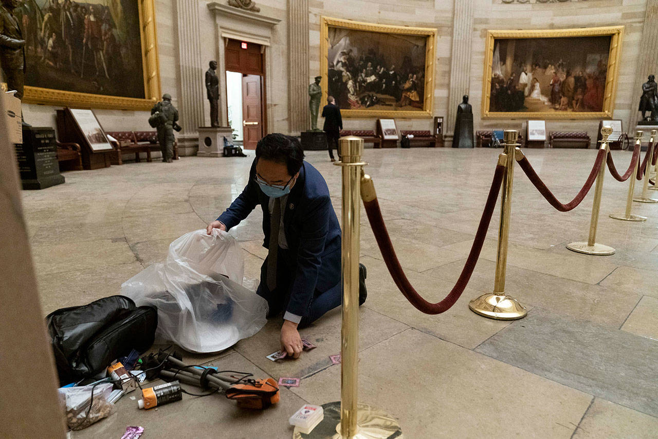 Rep. Andy Kim, D-N.J., cleans up debris and personal belongings strewn across the floor of the Rotunda in the early morning hours of Thursday after protesters stormed the Capitol in Washington on Wednesday. (AP Photo/Andrew Harnik)