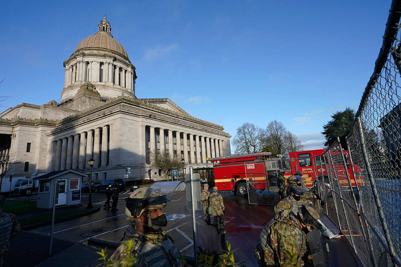 Members of the Washington National Guard stand along a perimeter fence as an Olympia Fire Department truck passes by on Sunday, Jan. 10, 2021, at the Capitol in Olympia. Washington Gov. Jay Inslee activated members of the National Guard this week to work with the Washington State Patrol to protect the Capitol campus ahead of the state Legislature opening its 2021 legislative session Monday, as several protests and rallies are expected. (Ted S. Warren/The Associated Press)
