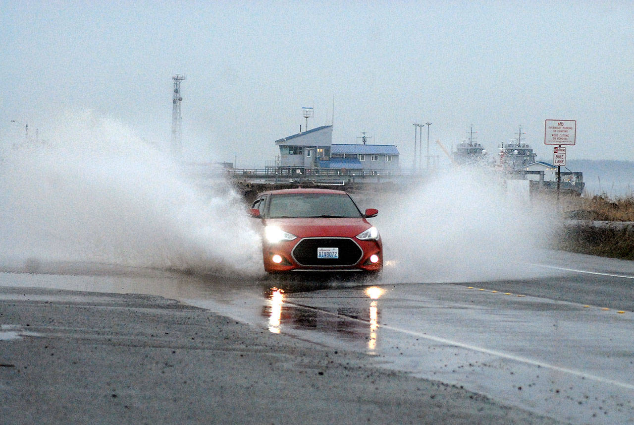 A car splashes through a puddle of standing water on Ediz Hook Road in Port Angeles on Tuesday after heavy overnight rains soaked much of the North Olympic Peninsula. Drier weather is expected today and Thursday with unsettled conditions forecast for Thursday night into Friday. (Keith Thorpe/Peninsula Daily News)