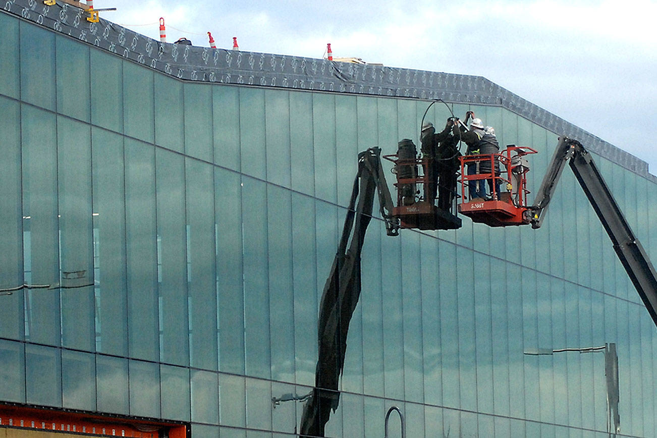 A construction crew works on the glass face of the new Field Arts & Events Hall on Thursday near the Port Angeles waterfront. The hall is expected to be put on hold when the exterior is complete pending additional fundraising to finish the approximately $50 million project, which will include a 1,000-square-foot art gallery, 500-seat performance hall, 300-seat conference area and a coffee shop. (Keith Thorpe/Peninsula Daily News)