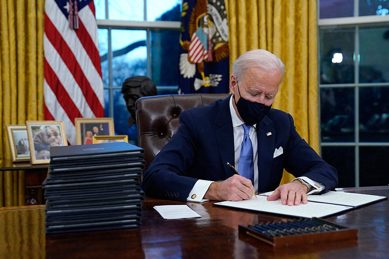 President Joe Biden signs his first executive order in the Oval Office of the White House on Wednesday, Jan. 20, 2021, in Washington. (AP Photo/Evan Vucci)