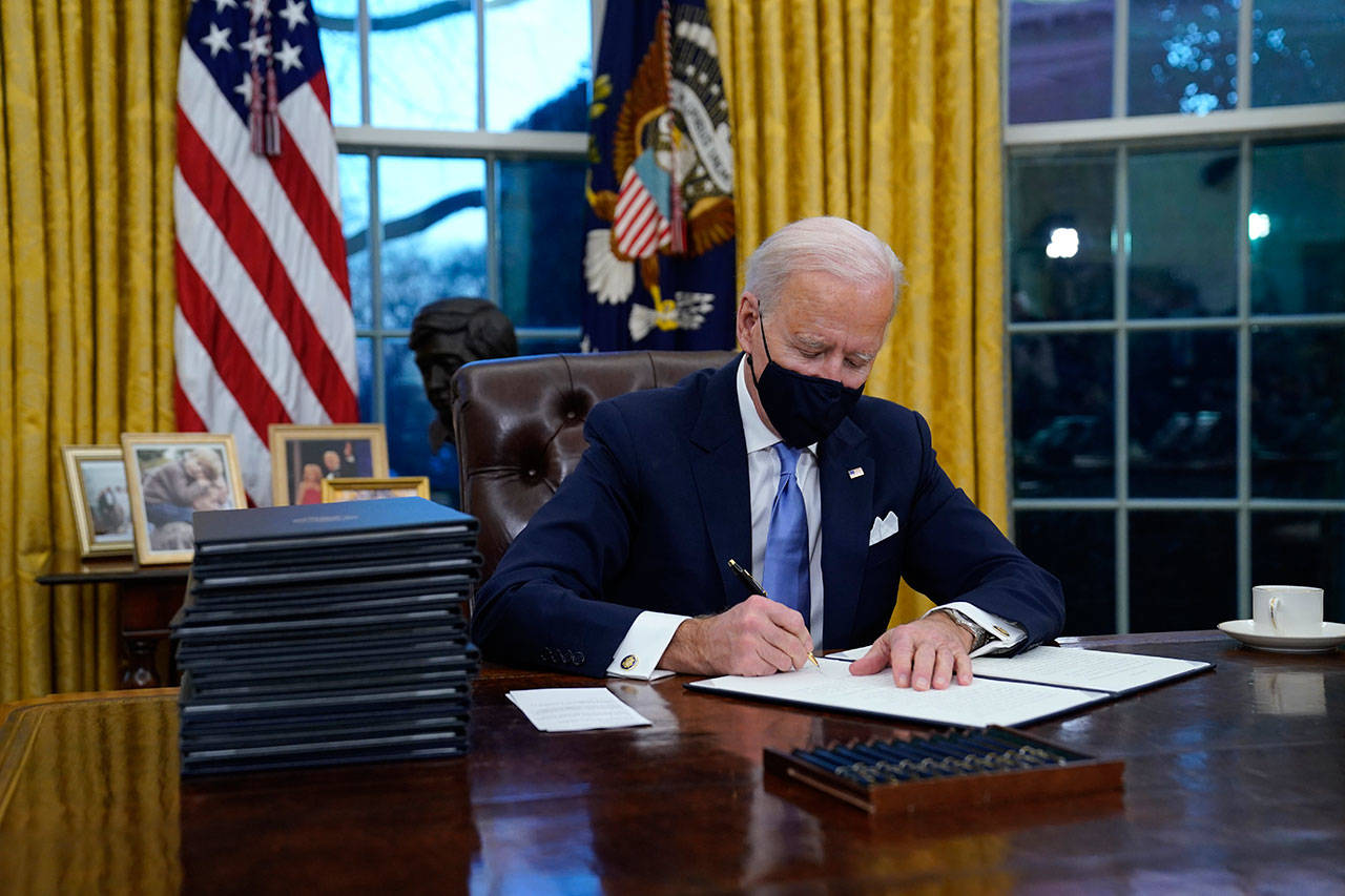 President Joe Biden signs his first executive order in the Oval Office of the White House on Wednesday, Jan. 20, 2021, in Washington. (AP Photo/Evan Vucci)