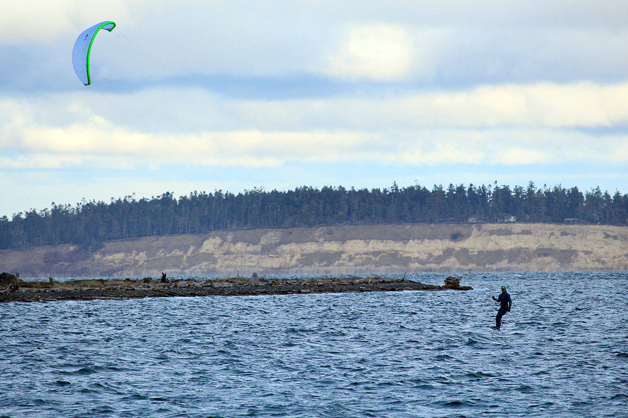 A kite surfer enjoys the wind and waves early afternoon Wednesday at Fort Worden State Park's beach near Point Wilson Lighthouse. Kitesurfing alone is a good way to social distance and stay active while COVID-19 remains a danger. (Zach Jablonski/Peninsula Daily News)