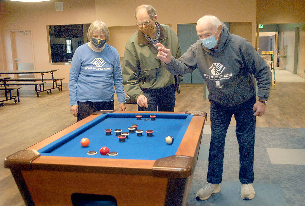 Boys & Girls Clubs of the Olympic Peninsula board member Norma Turner, left, and her husband, long time volunteer Gene Turner, right, play with a bumper pool table with construction facilitator Steve Zenovic in the game room of the new Port Angeles Units building, which has been named the Turner Clubhouse in honor of the Turners contributions to the clubs success. (Keith Thorpe/Peninsula Daily News)