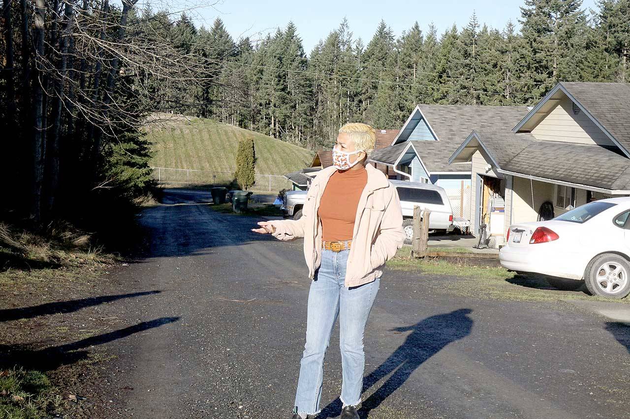 Sidney Murphy stands in the alley behind her home on West 13th Street in Port Angeles. The dirt alley also is the front driveway to several homes built on a sloping hillside, and it’s the only access for emergency services. (Dave Logan/For Peninsula Daily News)
