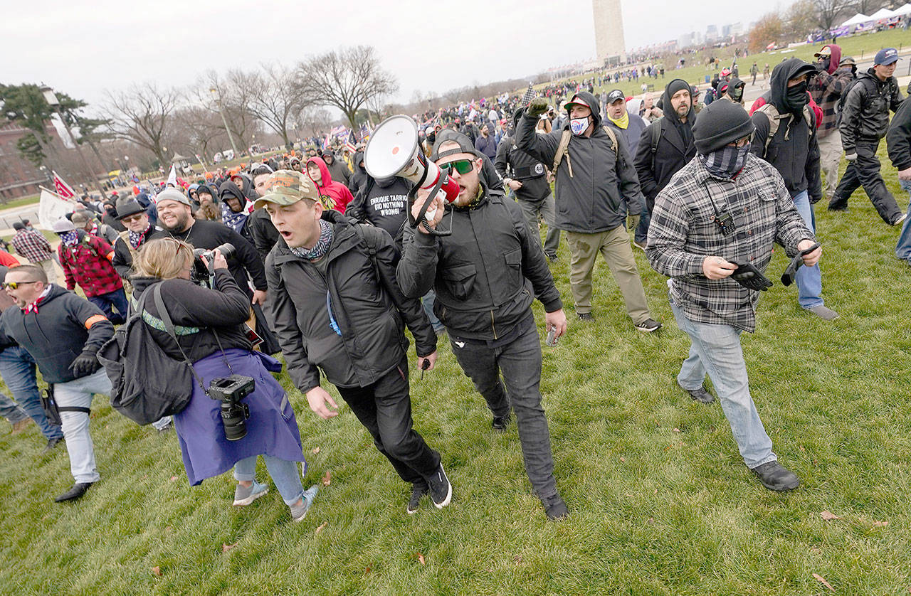 In this Jan. 6 photo, Ethan Nordean, with backward baseball hat and bullhorn, leads members of the far-right group Proud Boys in marching before the riot at the U.S. Capitol. Nordean, 30, of Auburn, Washington, has described himself as the sergeant-at-arms of the Seattle chapter of the Proud Boys. The Justice Department has charged him in U.S. District Court in Washington, D.C., with obstructing an official proceeding, aiding and abetting others who damaged federal property, and knowingly entering or remaining in a restricted building. He asked a judge Monday, Feb. 8, 2021, to release him from detention pending trial. (AP Photo/Carolyn Kaster)